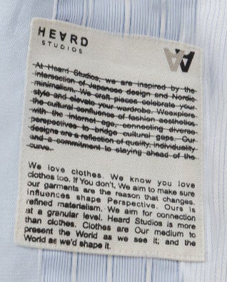 Close-up of a label on a light blue striped shirt with text.